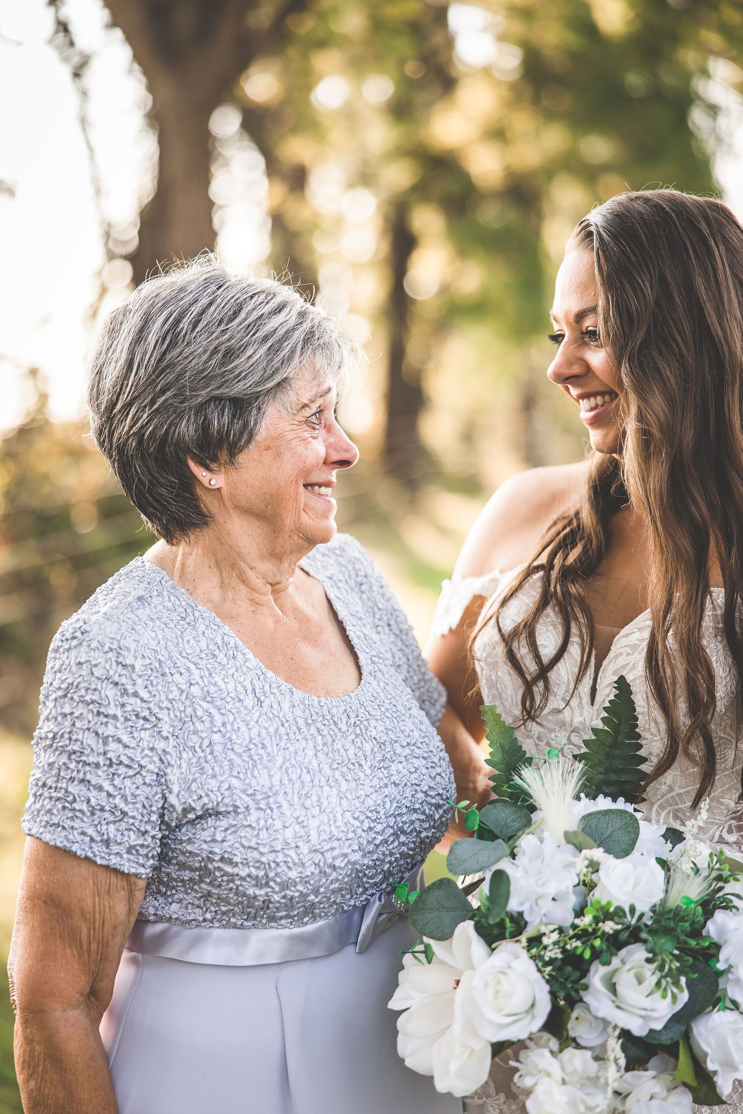 Candid moments of joy shared between family members in silver and white attire at an outdoor wedding celebration.