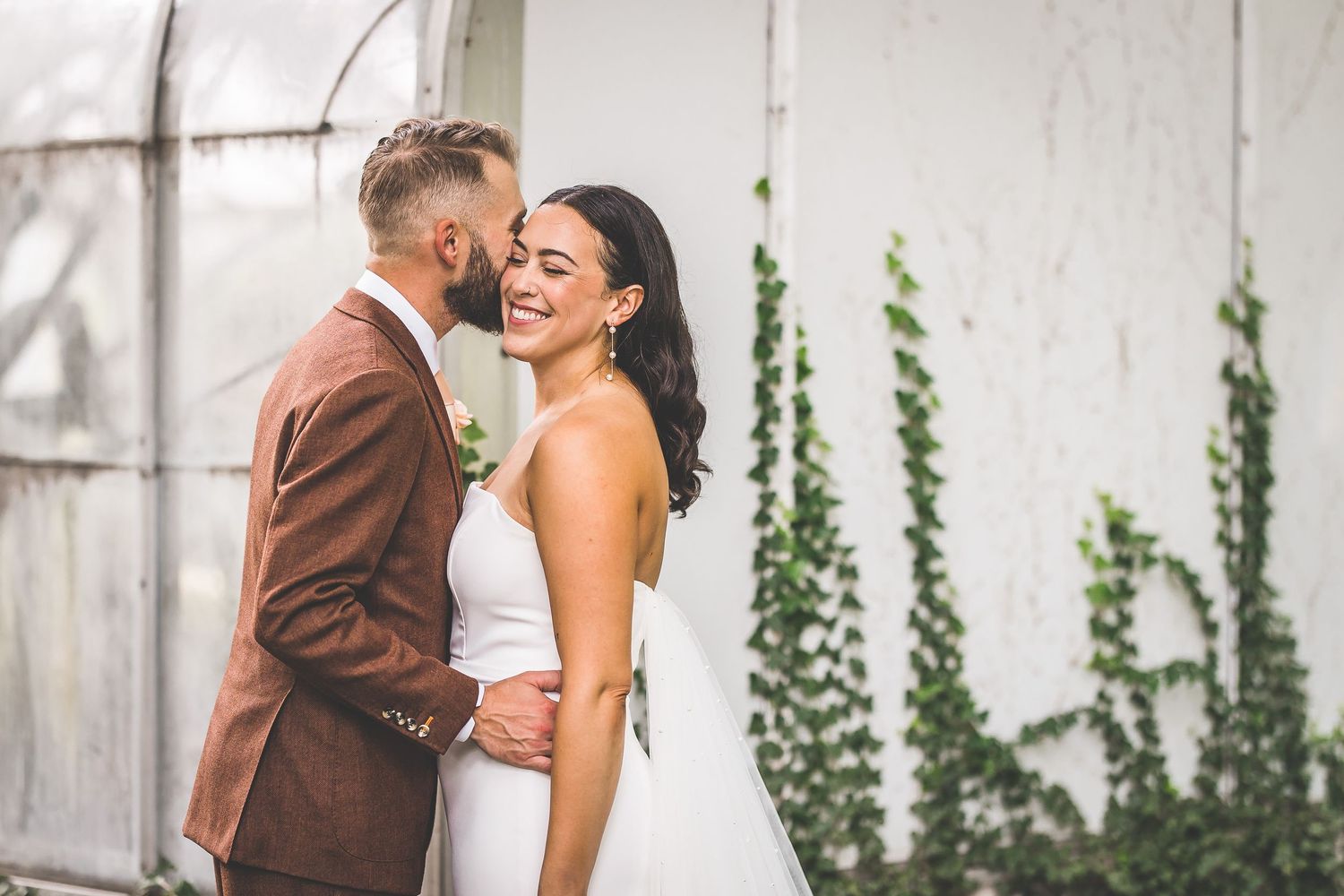 A romantic outdoor wedding photoshoot against a rustic backdrop with ivy covered walls.