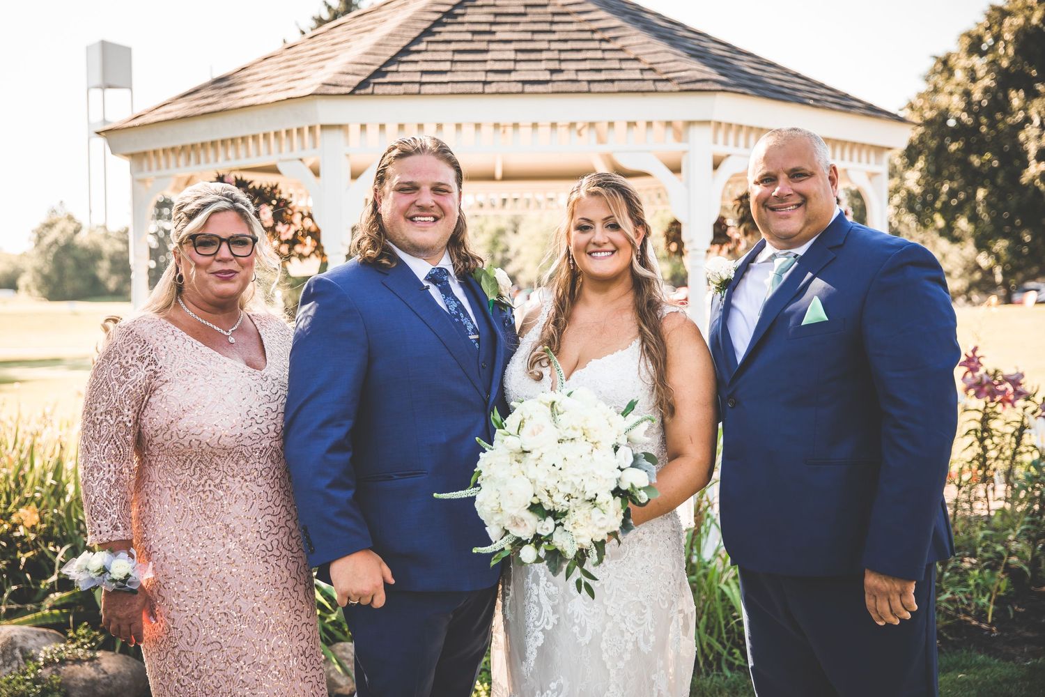 Wedding group photo with navy and blush attire against architectural backdrop.
