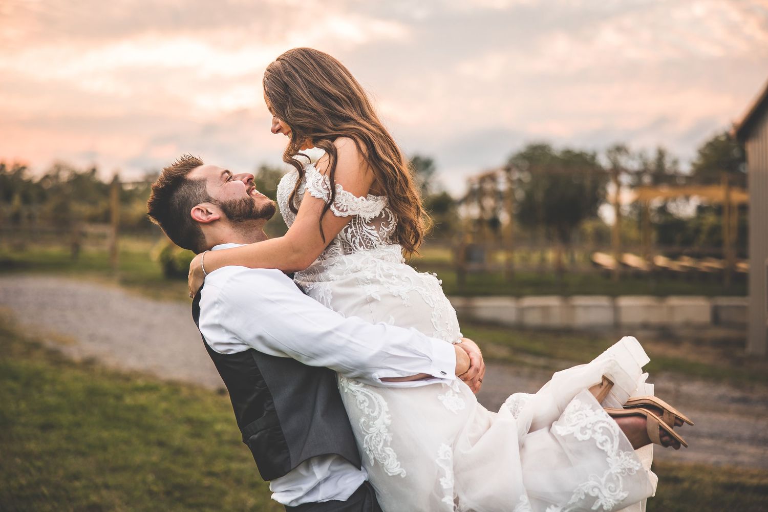 Wedding couple embracing in a field during golden hour with flowing white dress.