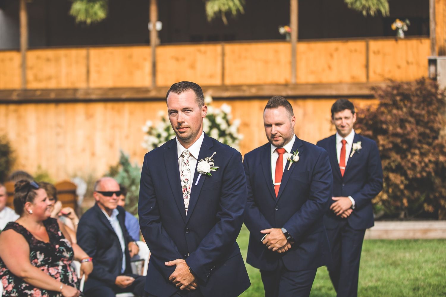 Wedding party members stand at attention during outdoor ceremony.