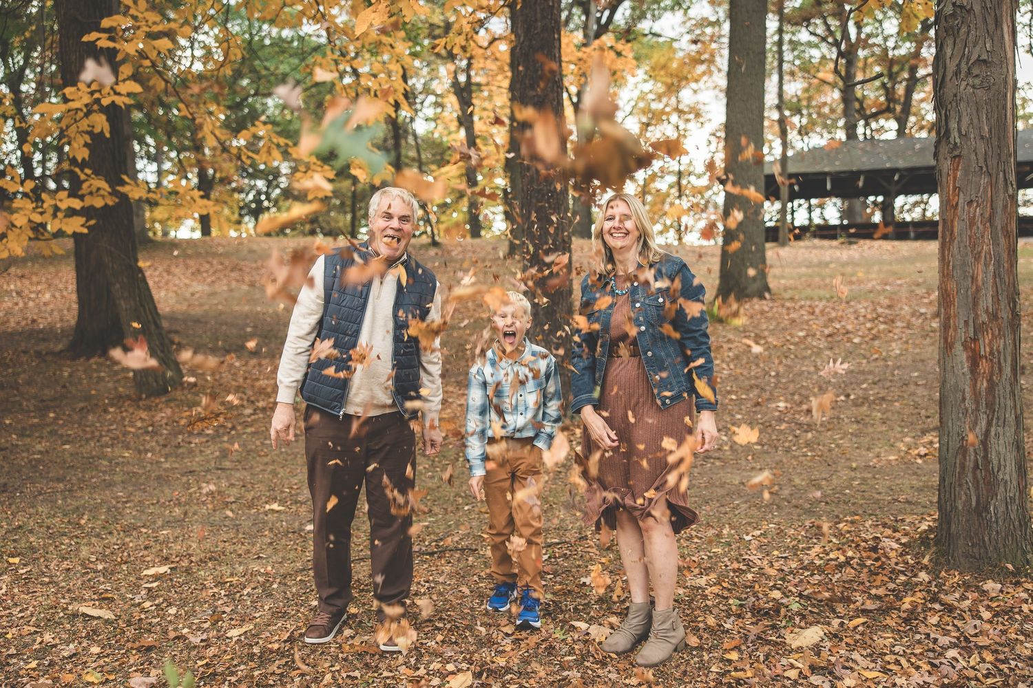 Group walking together through a forest path covered in fallen autumn leaves.
