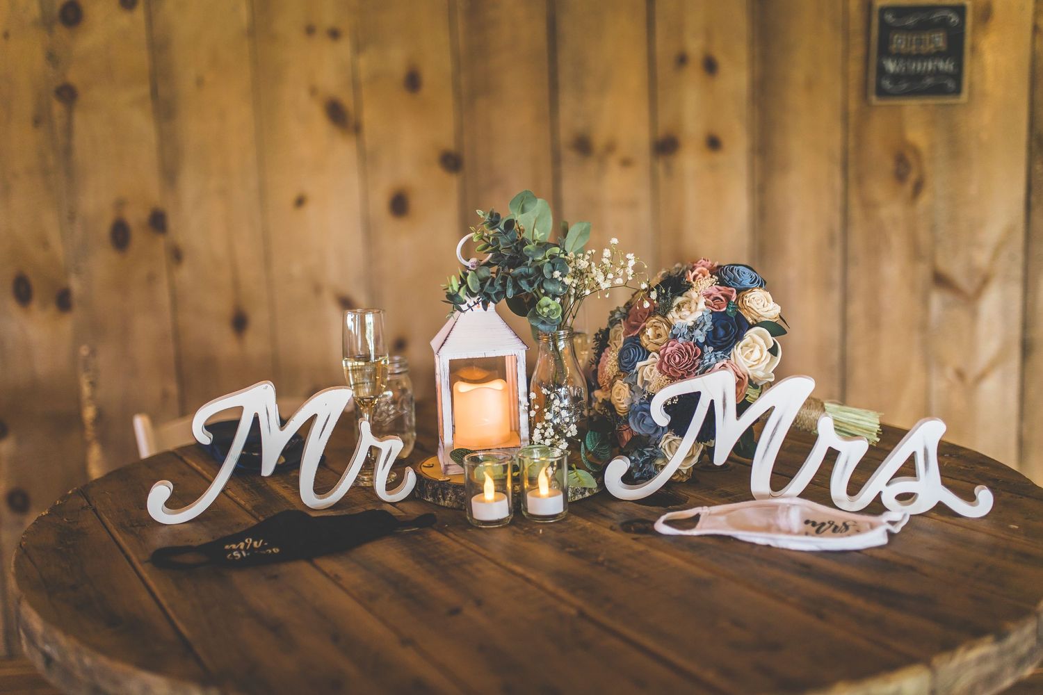 Wooden decorative signs and wedding decor arranged against rustic barn wall.