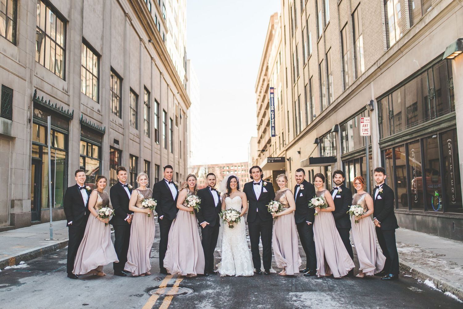 Wedding party poses along urban street with classic architecture.