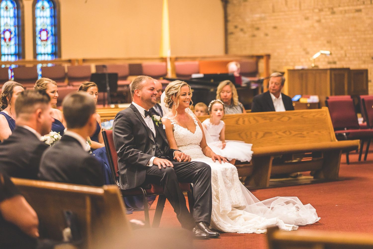 Church interior with stained glass windows during a wedding ceremony.