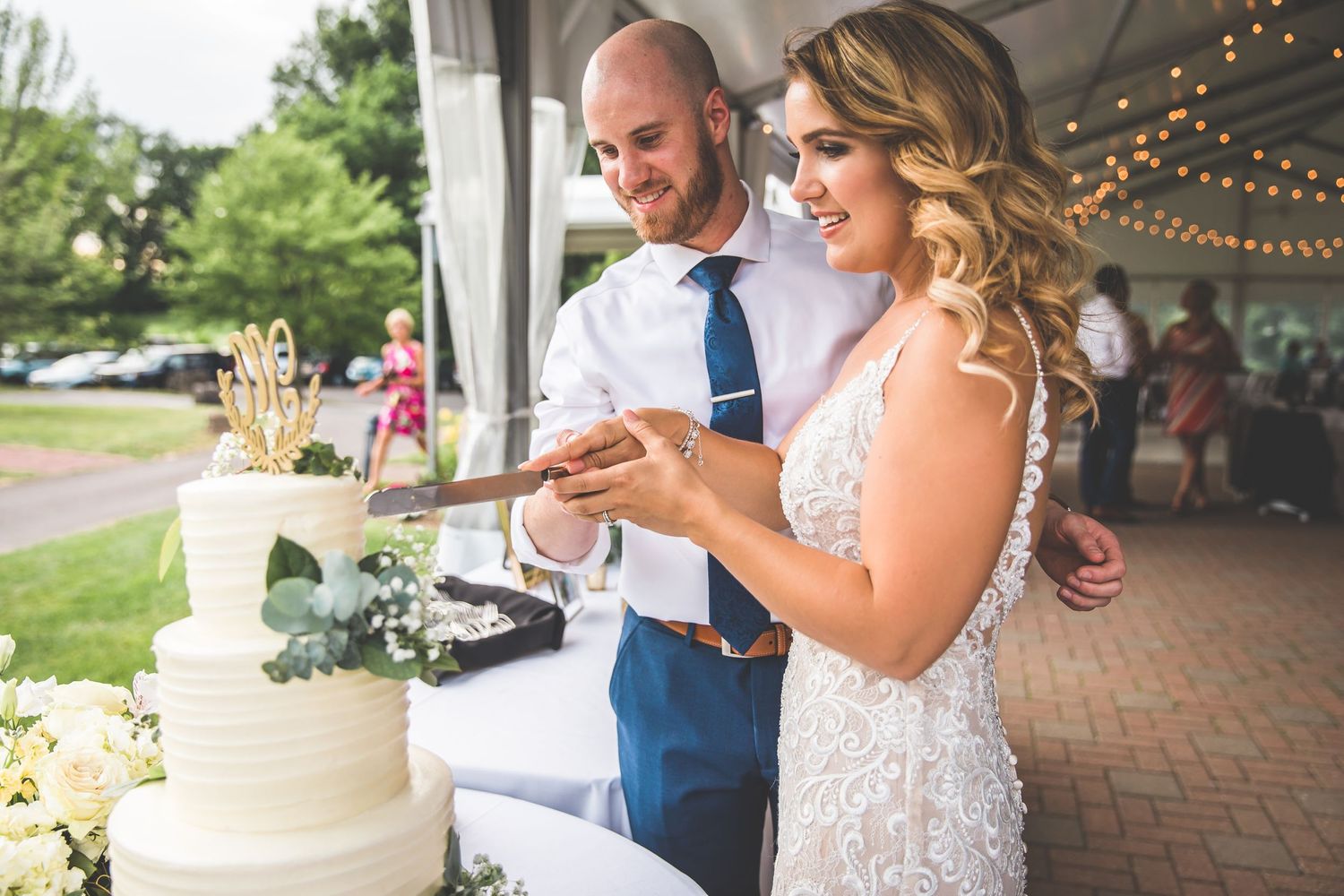 A couple cutting their elegant white wedding cake together at their reception.