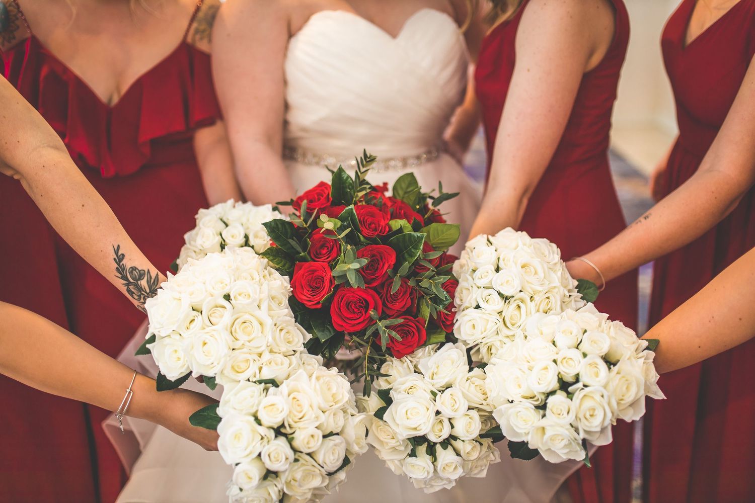 Wedding bouquets featuring red roses and white hydrangeas held together in circle.