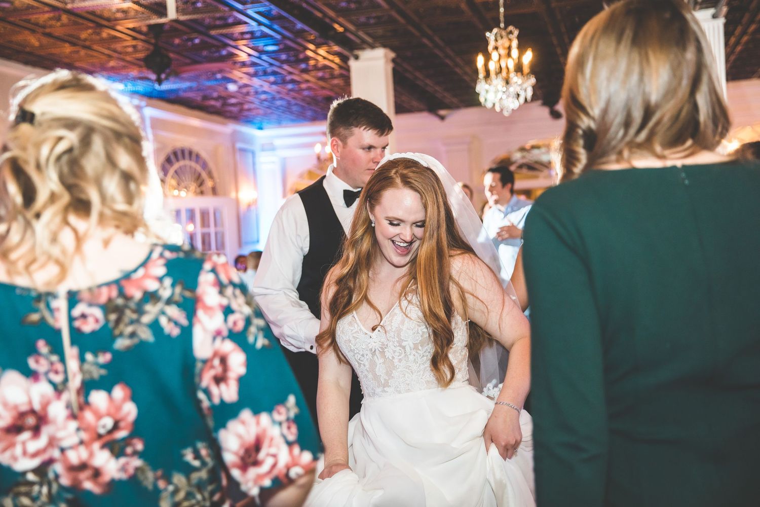 Wedding celebration with guests dancing under crystal chandeliers and blue mood lighting.