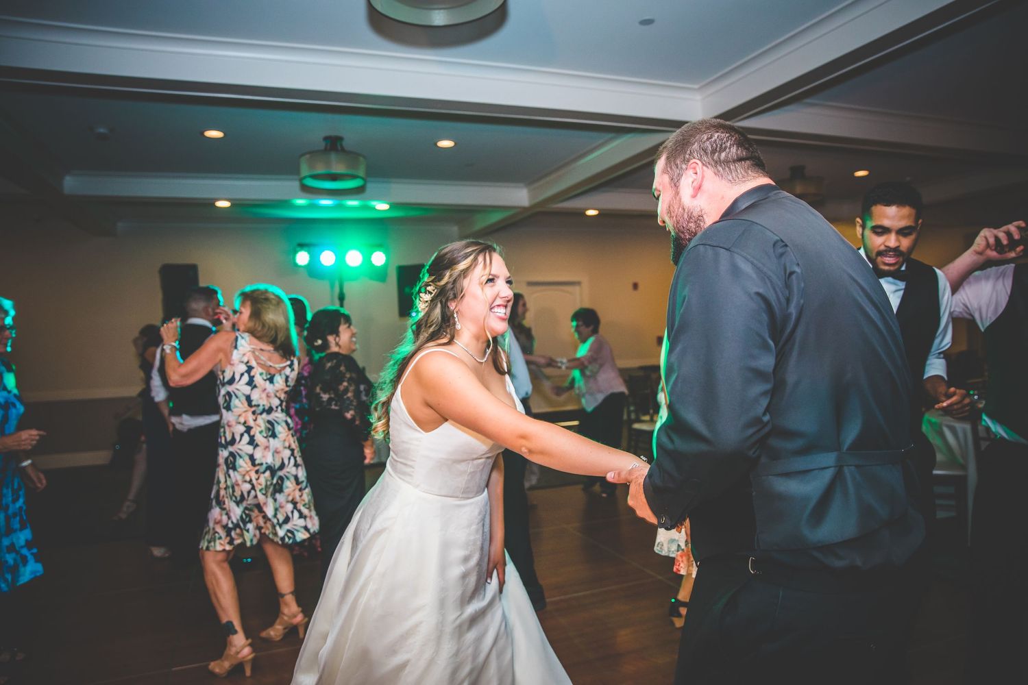 Wedding reception dance floor with colorful lighting and guests dancing.