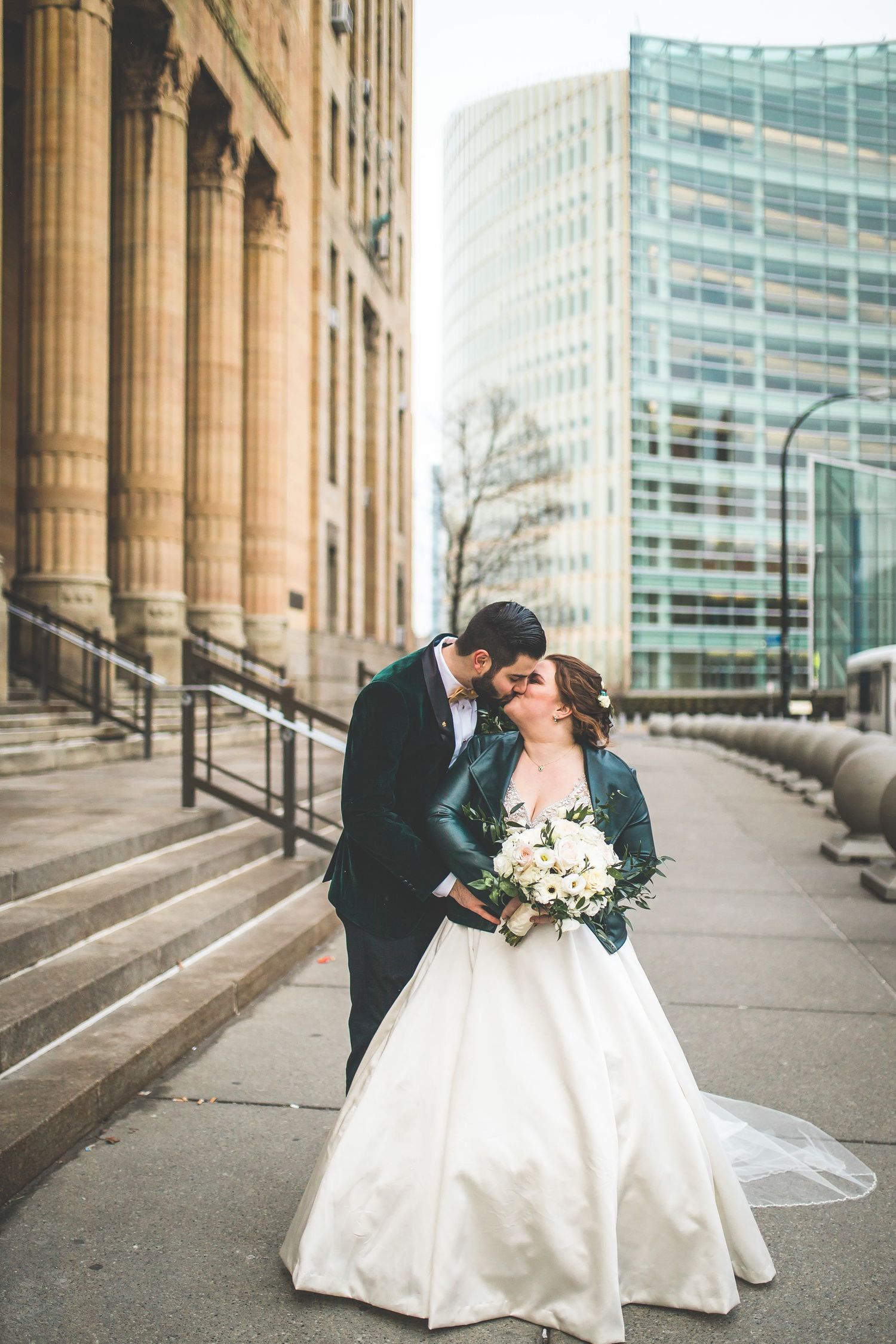 Wedding couple poses for romantic portraits along classical building exterior.