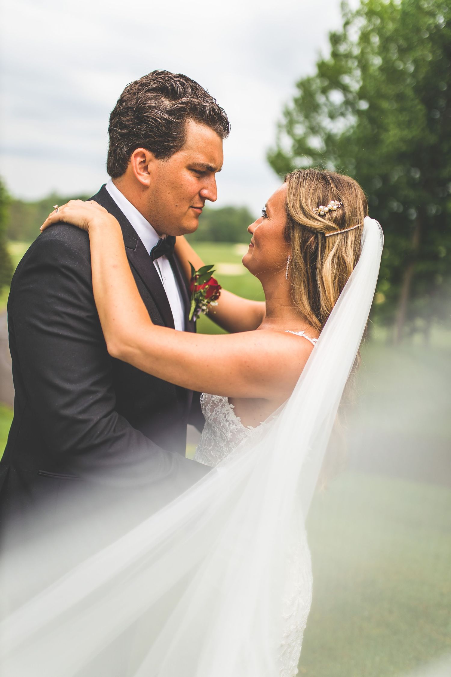 Romantic wedding couple shares intimate moment in misty outdoor garden setting.