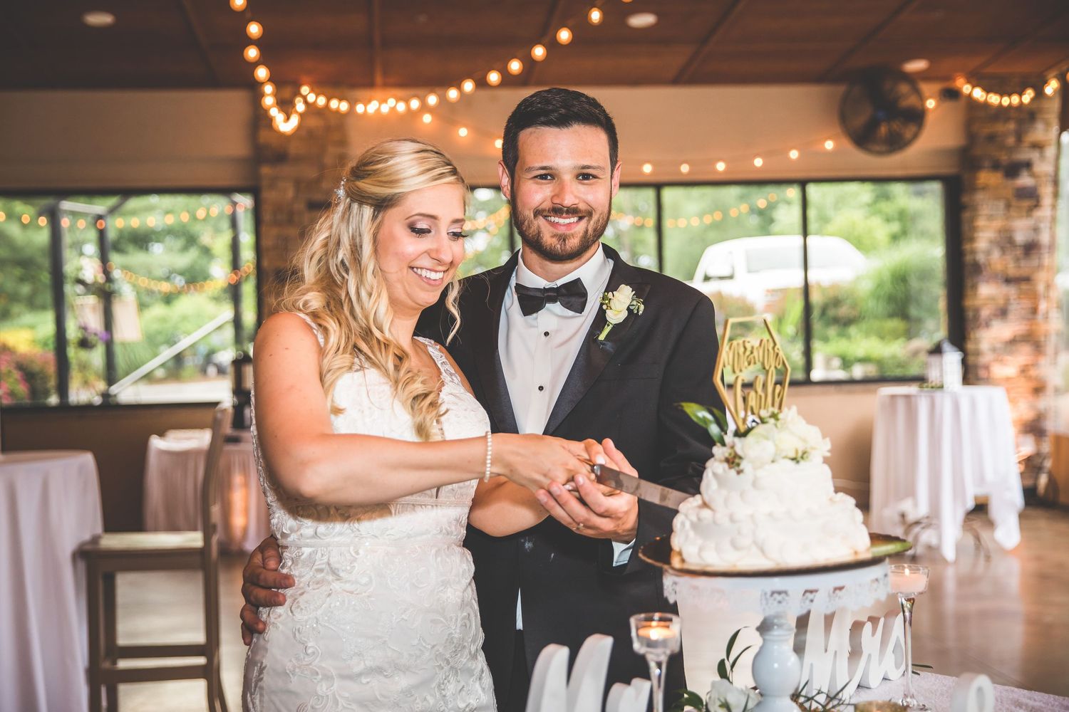 A couple cutting their wedding cake together at their reception.