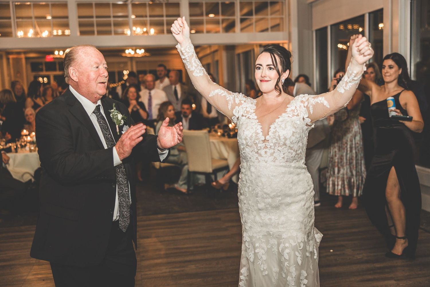 A celebratory dance moment captured during a wedding reception with guests applauding.