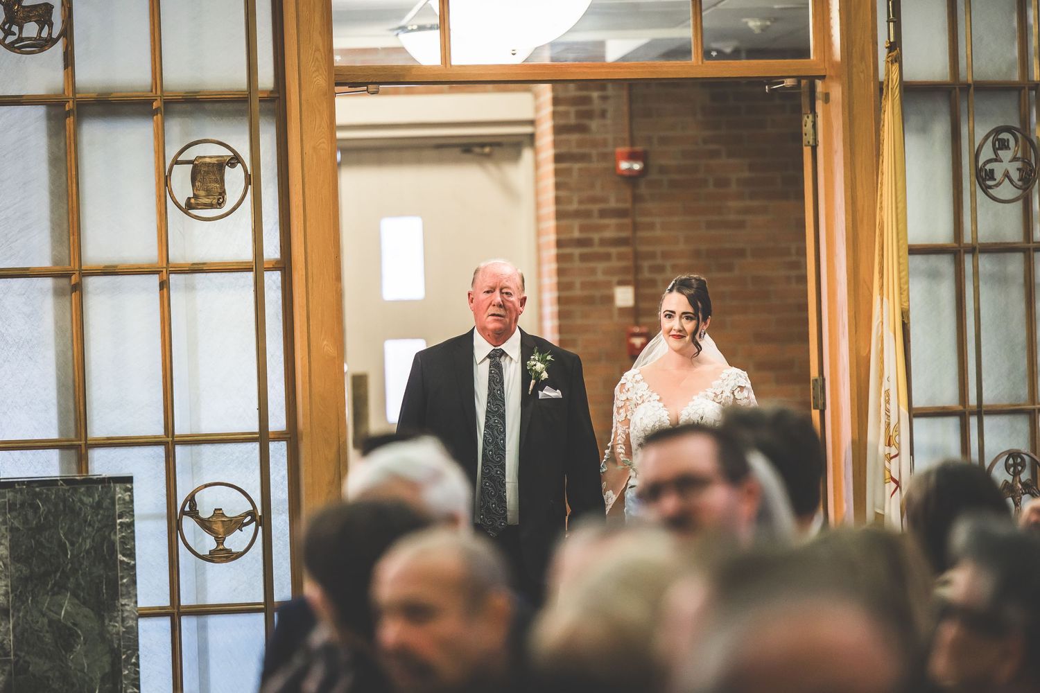 Wedding processional down church aisle with guests seated in wooden pews.