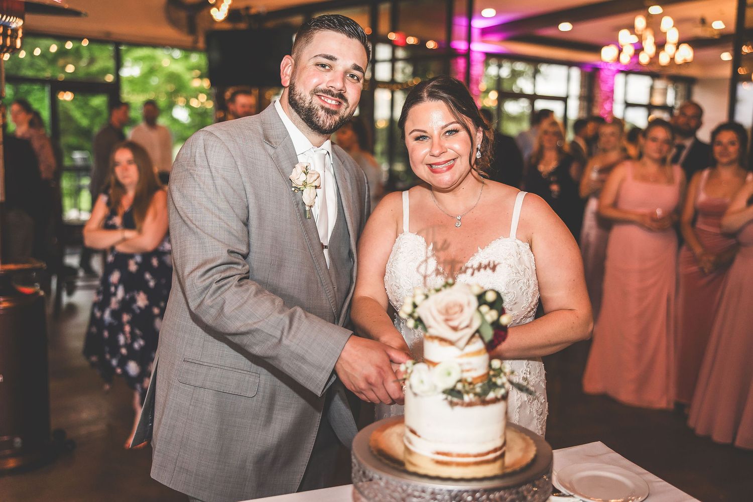 Elegant wedding reception with cake cutting moment and pink decor details.