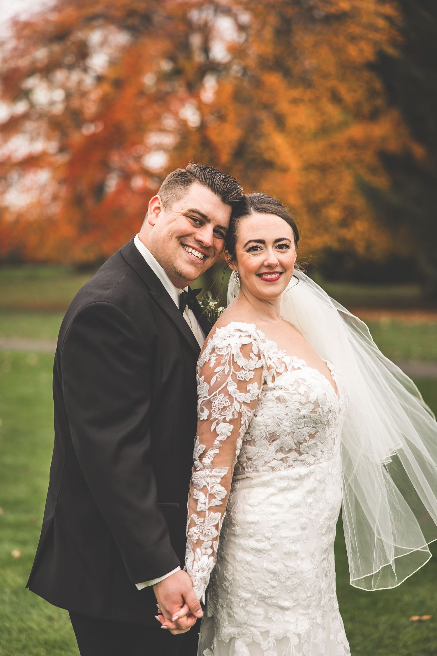 Wedding couple shares intimate moments in a park with beautiful fall colors in the background.