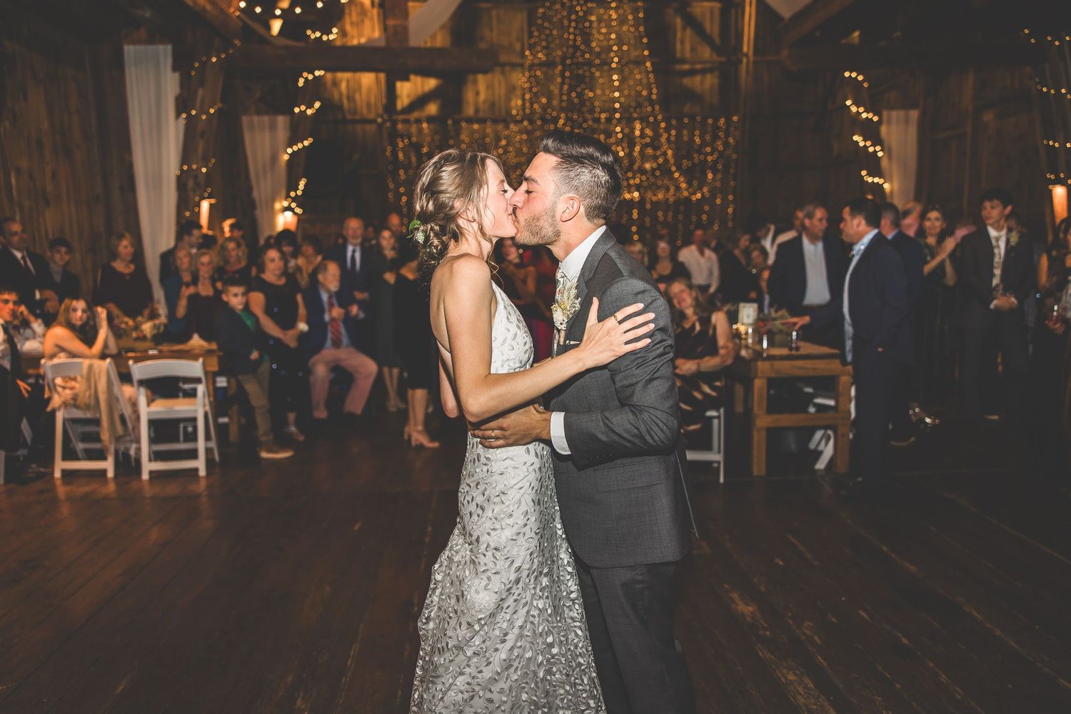 Newlyweds dancing together at their reception with guests watching in the background.