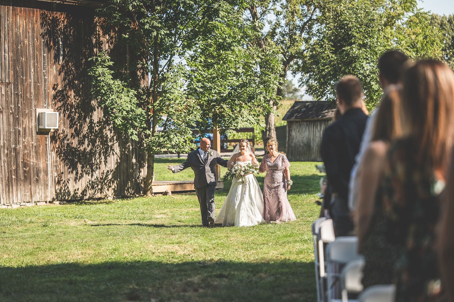 Wedding ceremony guests gathering outside a rustic barn venue.