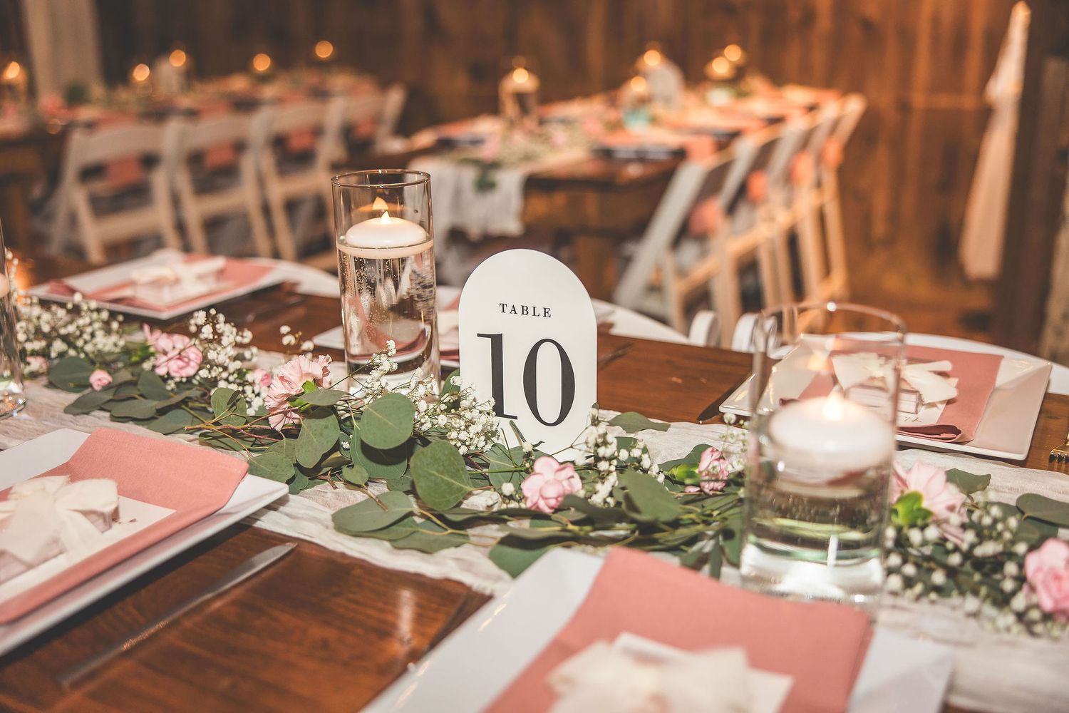 Wedding table number 10 displayed with greenery runner and candle centerpiece.