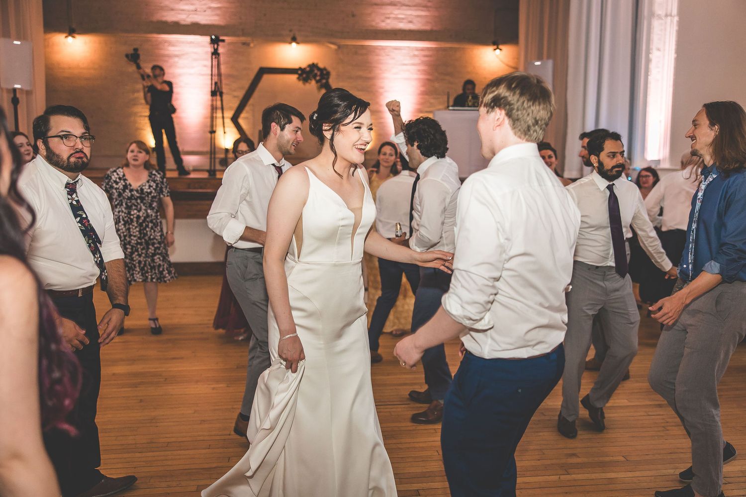 Wedding party dancing and celebrating on a wooden dance floor at an evening reception.