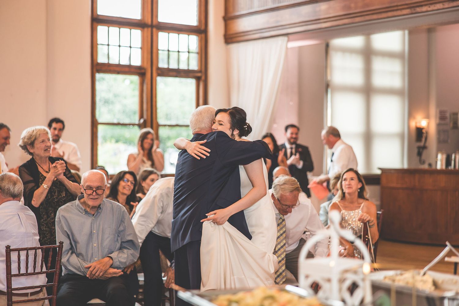 Wedding reception guests mingle and celebrate in an elegant wood-paneled venue.