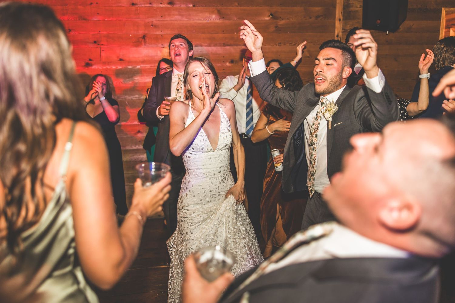 Festive dance party with red ambient lighting and wooden walls.