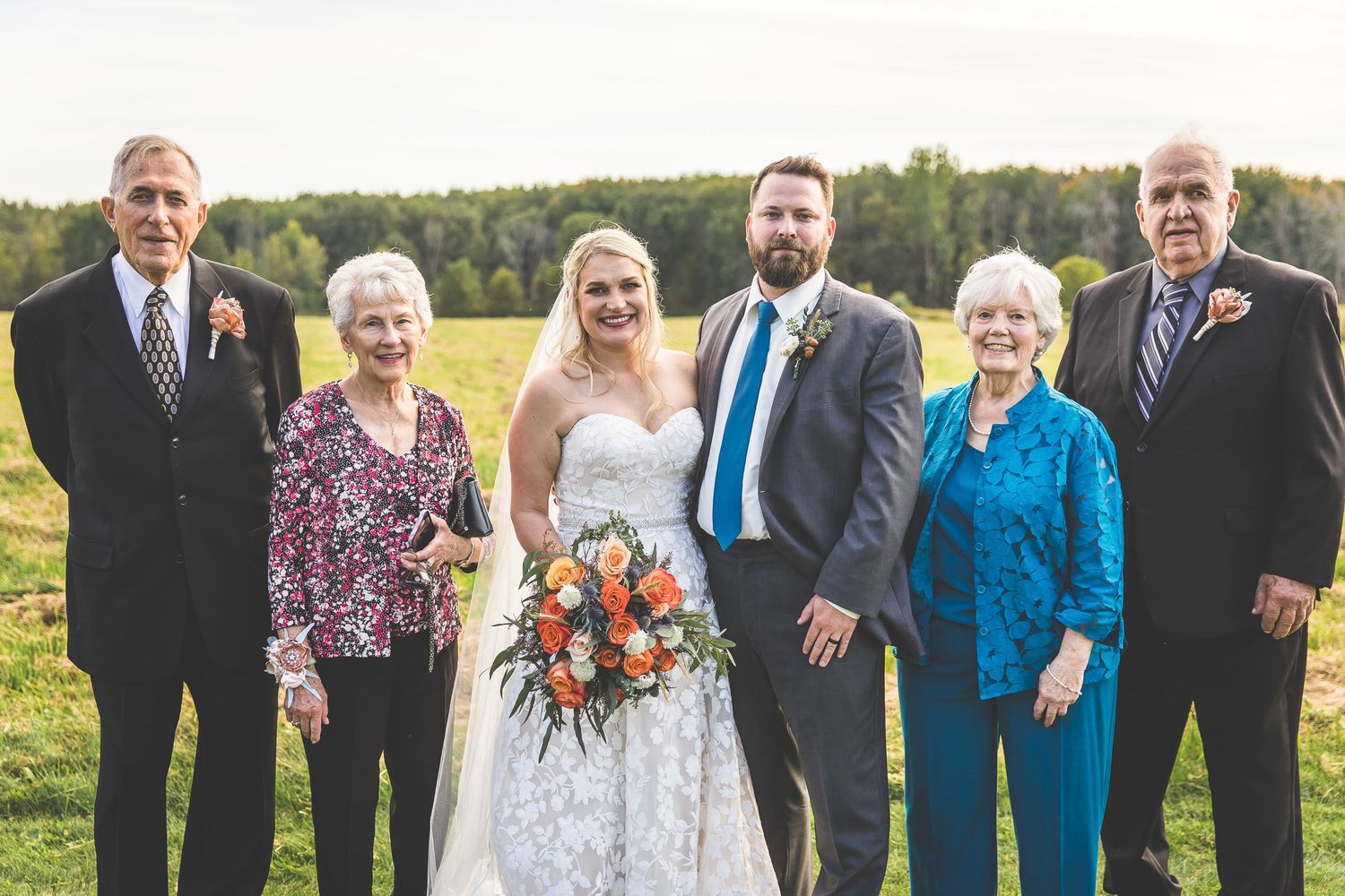 Extended family and wedding party gathered for formal outdoor portrait.