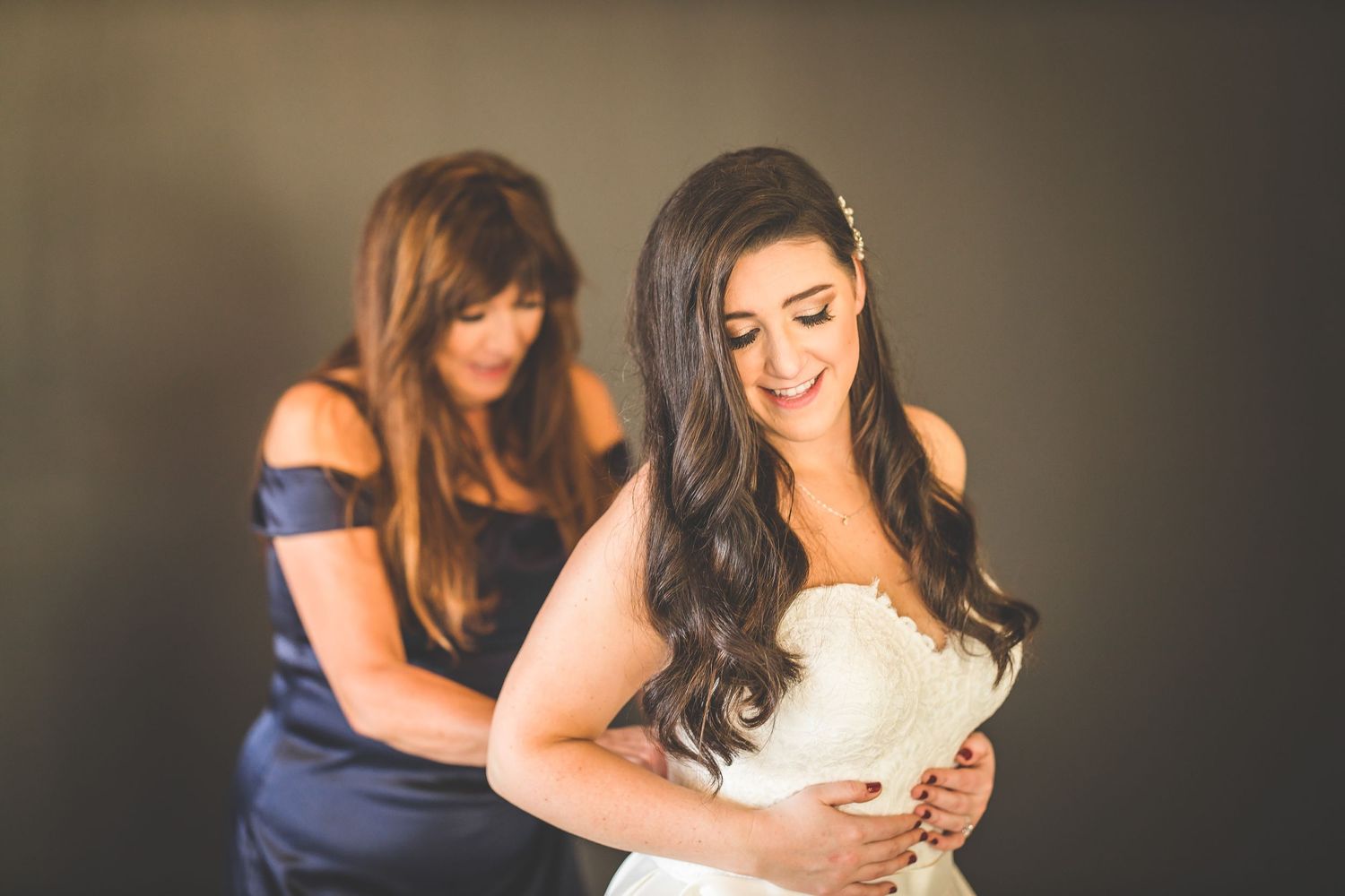 Bridesmaids in navy and white dresses embrace during an emotional wedding day moment.