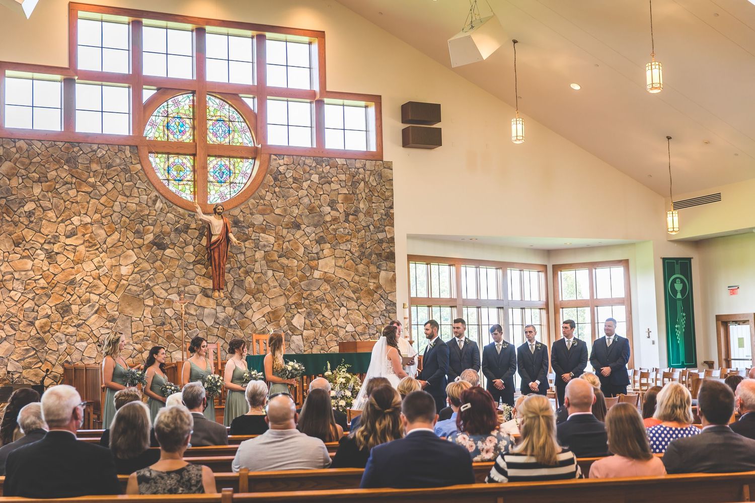 Wide angle shots of a church wedding ceremony showing guests seated in wooden pews.