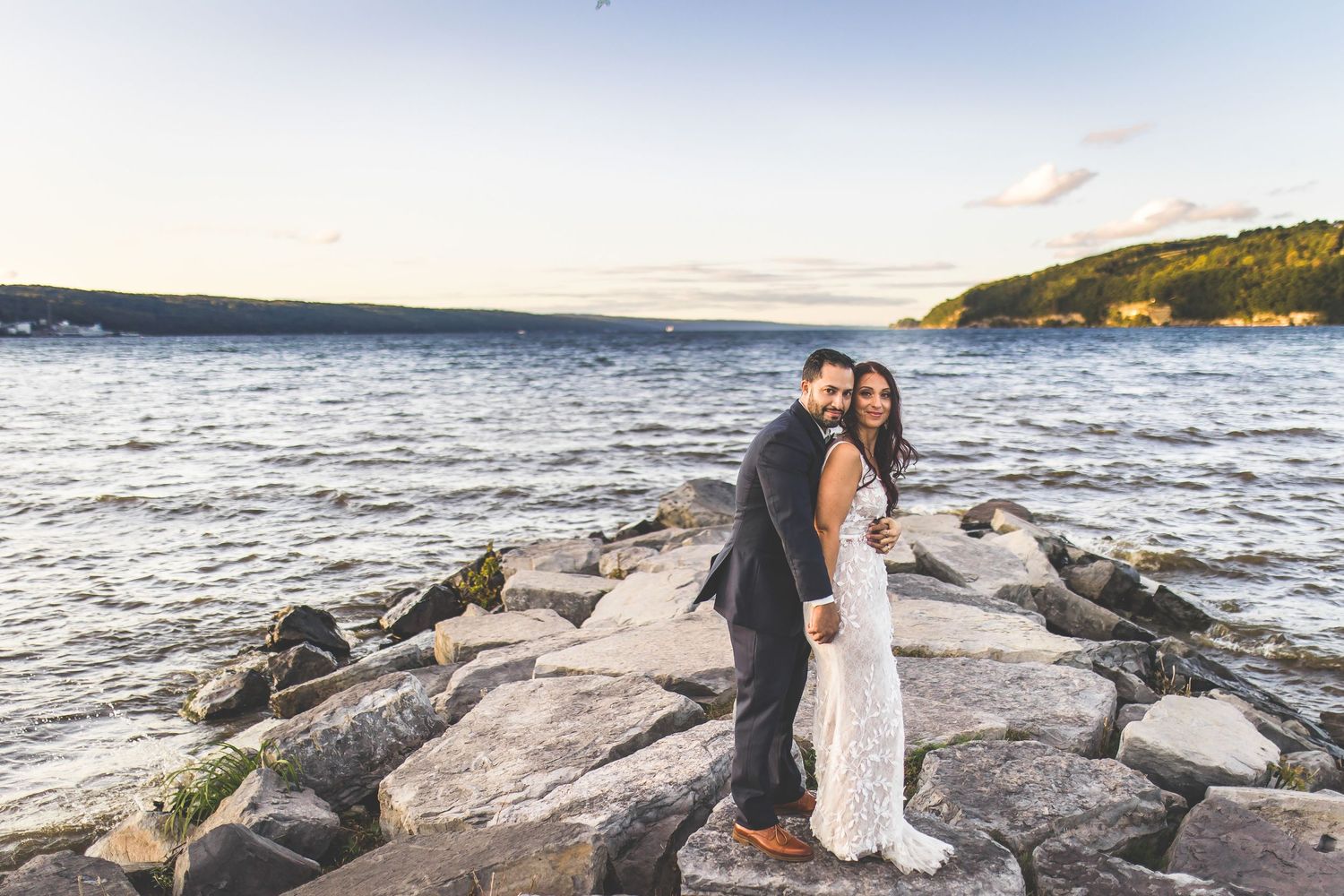 Romantic coastal wedding photoshoot on rocky shoreline with ocean views.