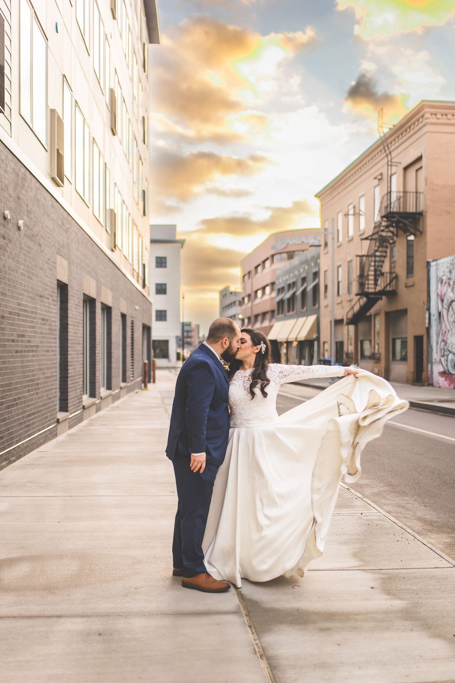 Wedding couple embracing during sunset in front of historic city buildings.