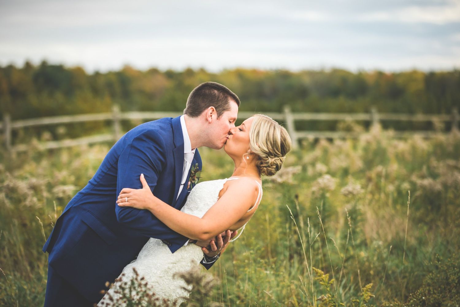 Romantic couple shares intimate moments in a golden field during sunset photo session.