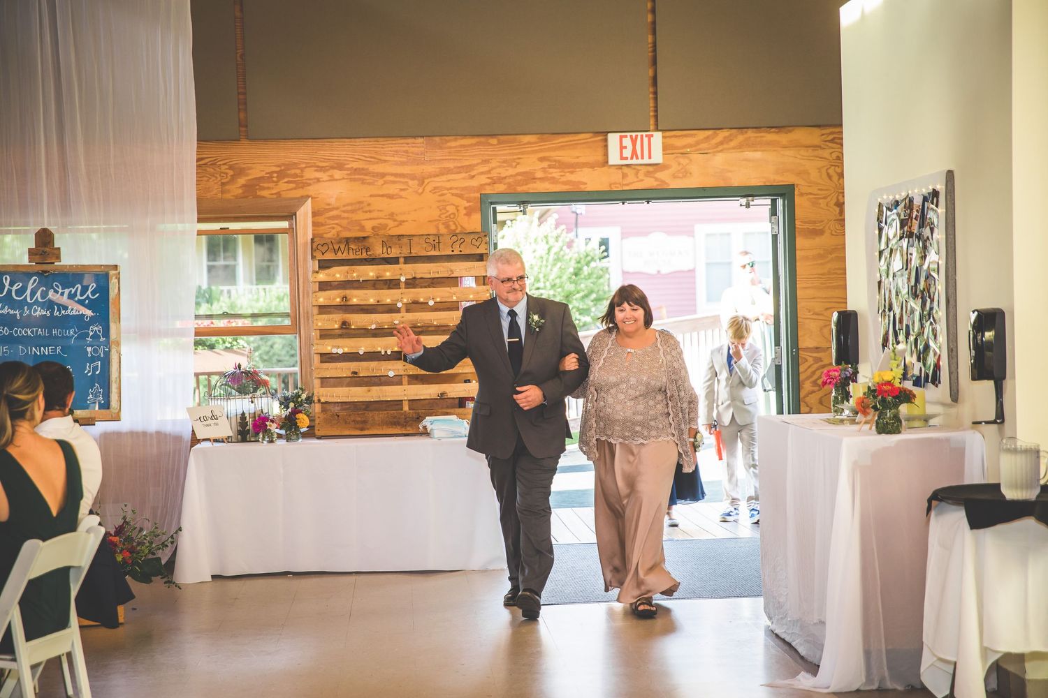 Wedding guests entering a rustic reception venue with wooden walls and white decor.