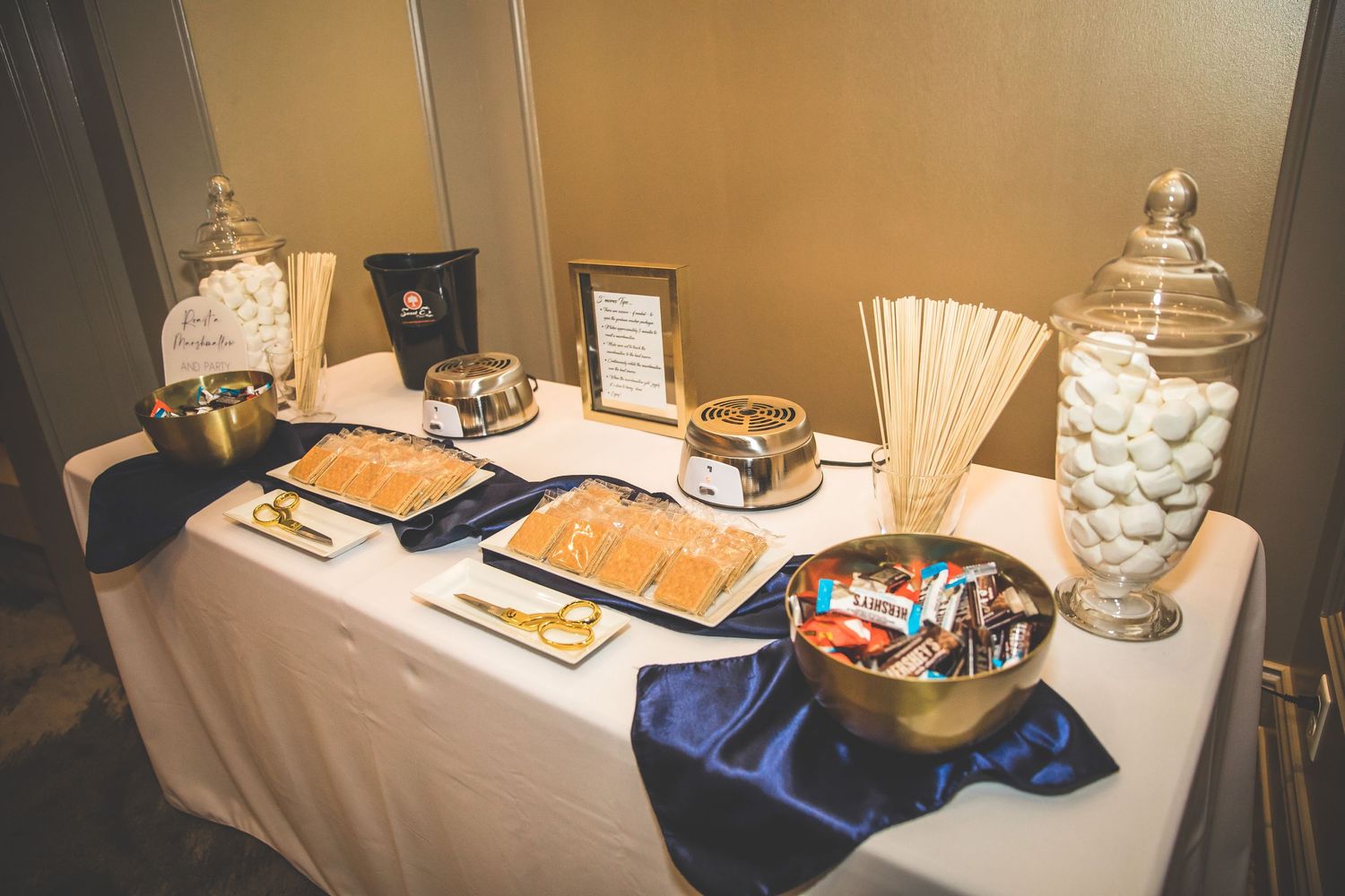 Wedding reception dessert table with elegant displays and decorative settings.