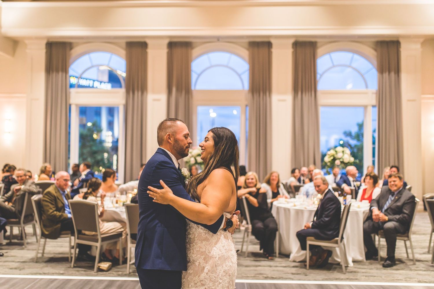 Elegant ballroom wedding venue with arched windows and romantic lighting.