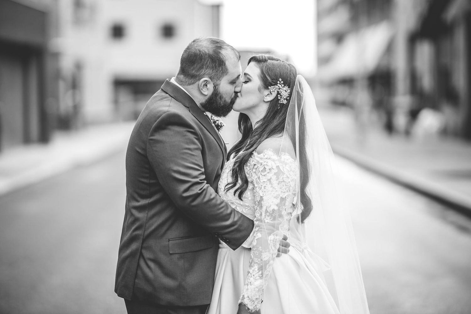 Wedding couple embraces on empty city street with brick buildings and graffiti.