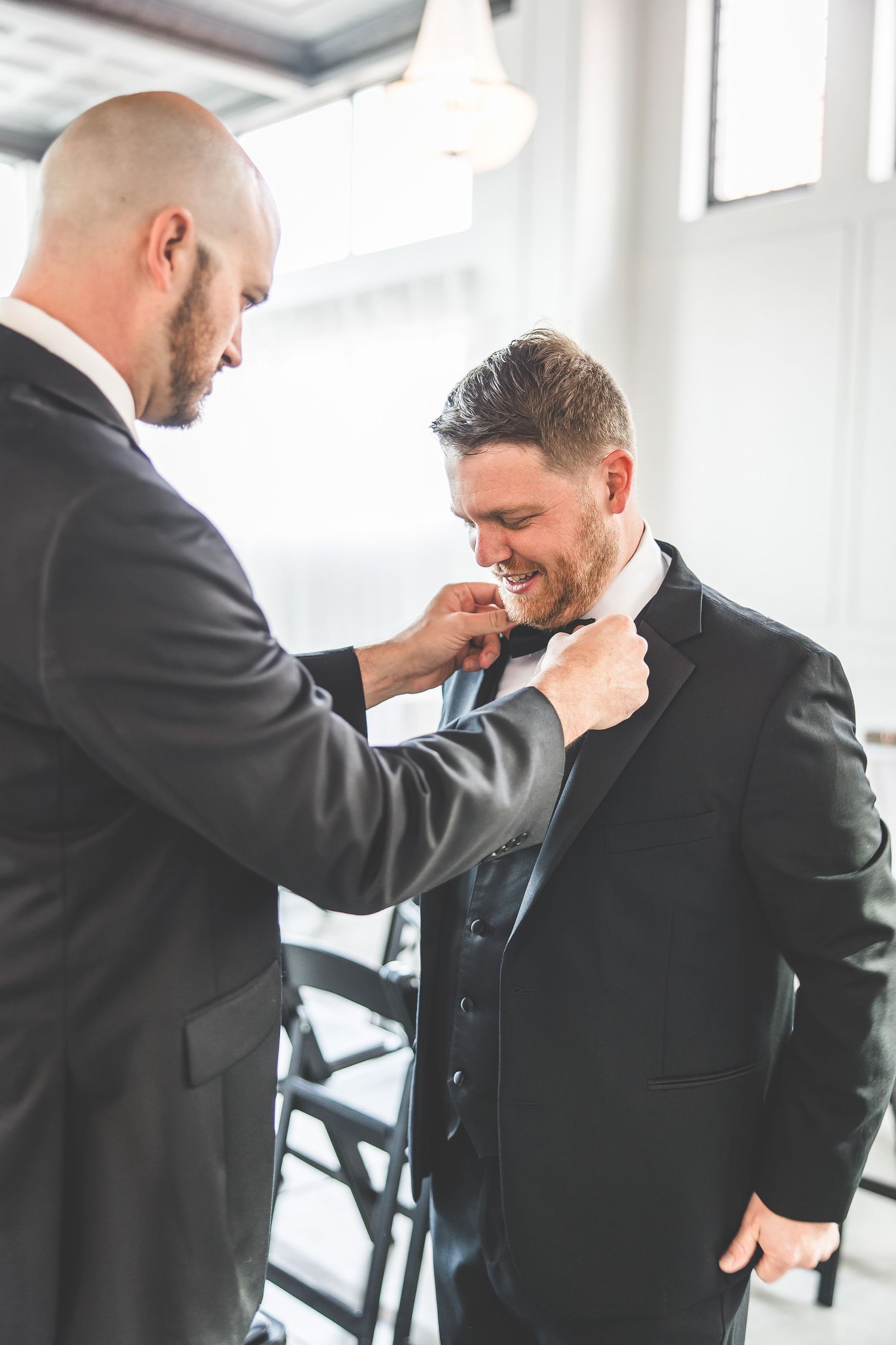 Wedding preparation moment captured in natural light against white walls.