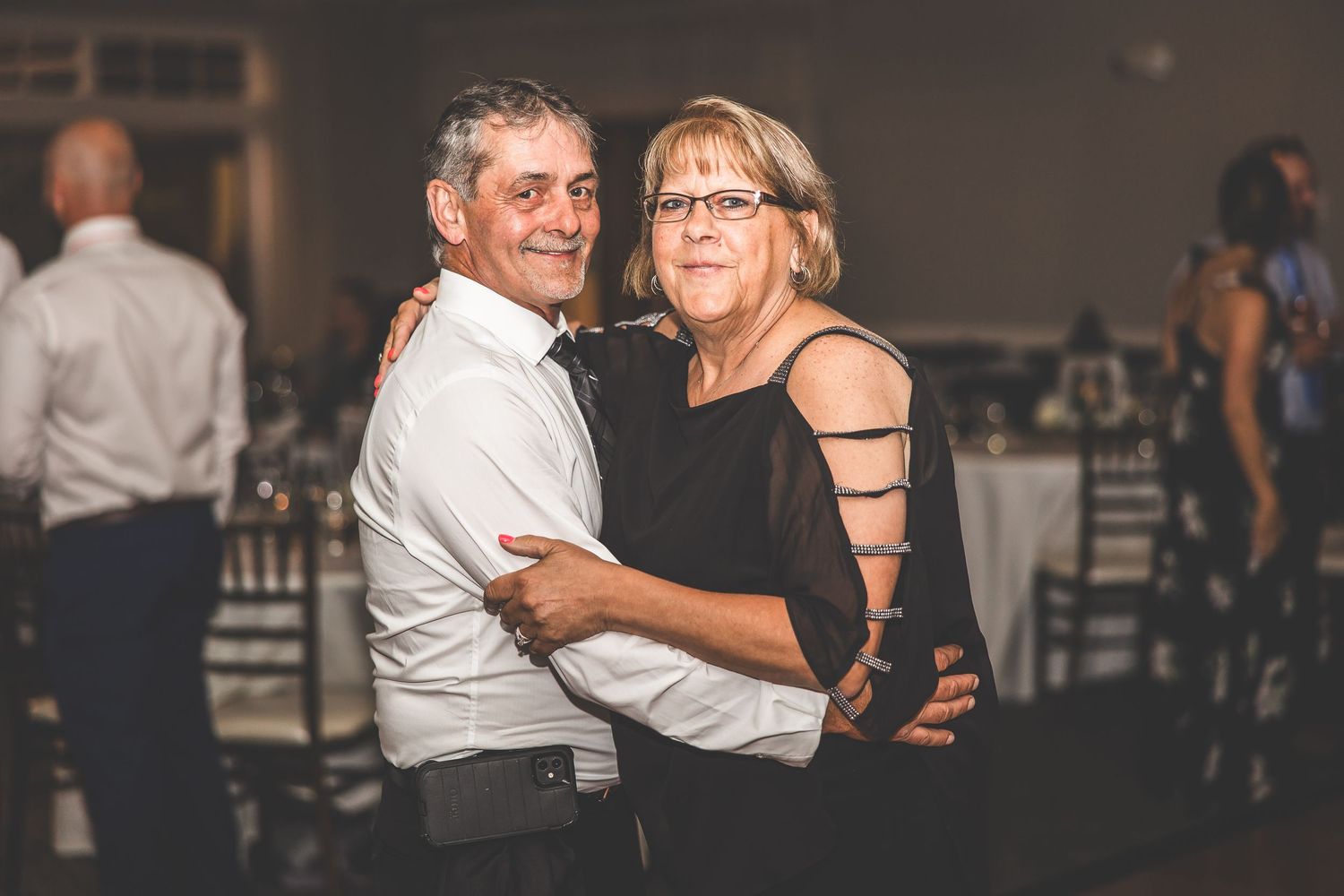 Couples dancing together at evening wedding reception with ambient lighting.