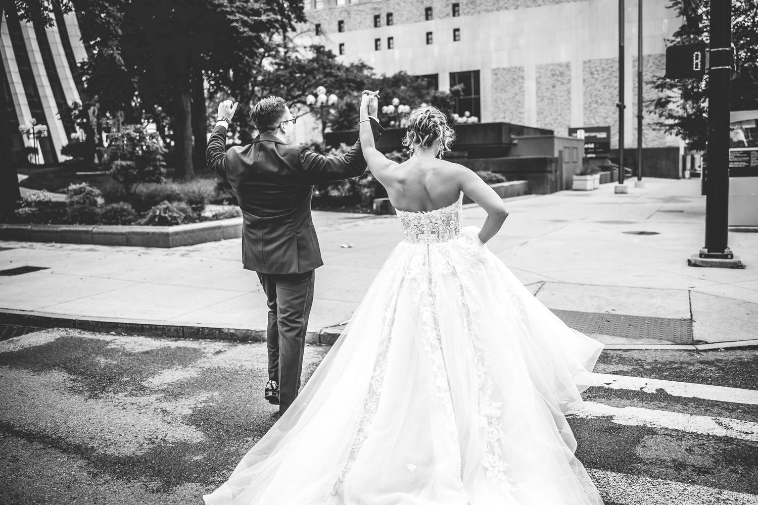 Black and white wedding portraits showing couple walking through an urban park setting.