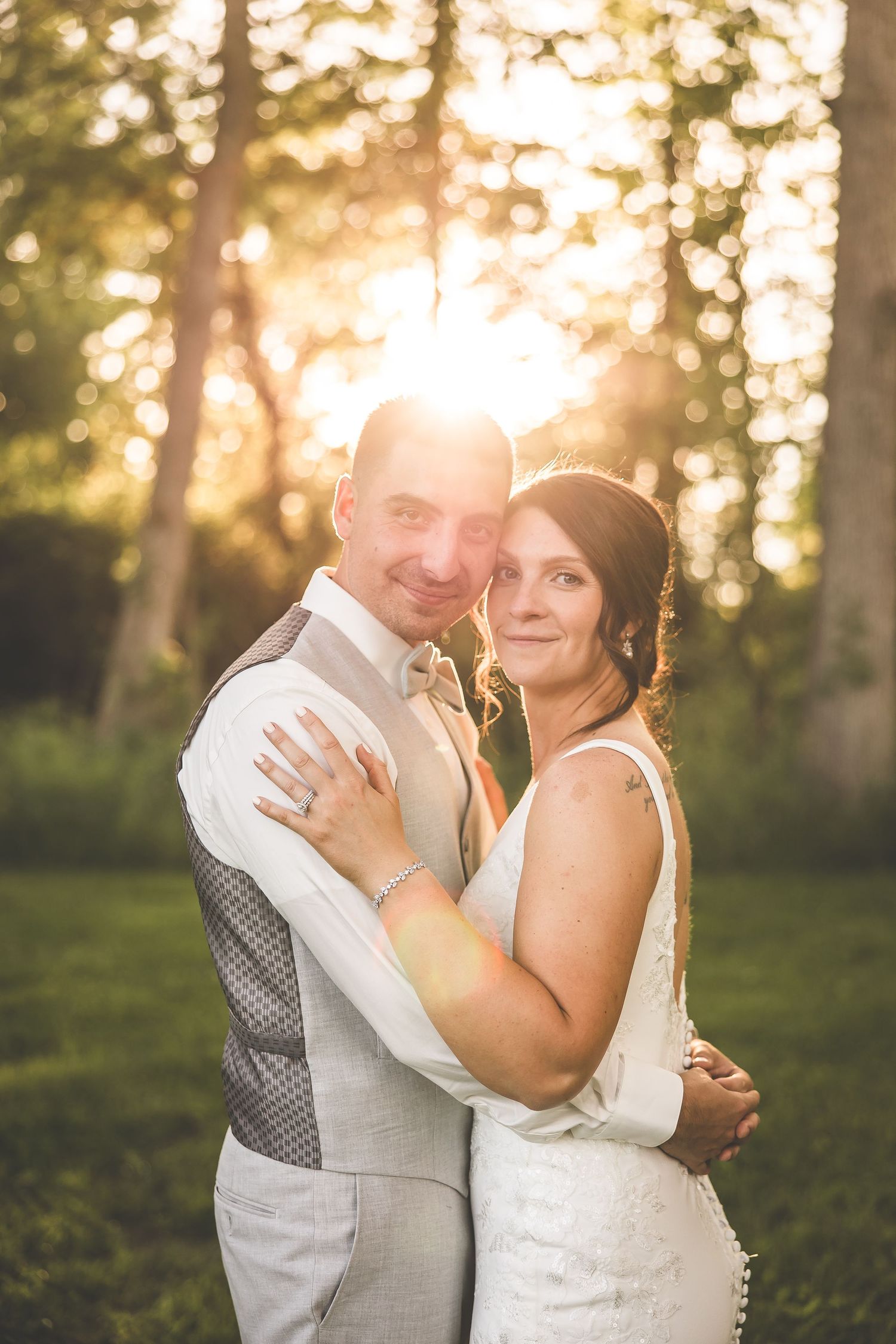 A tender embrace captured during sunset with golden light streaming through trees.