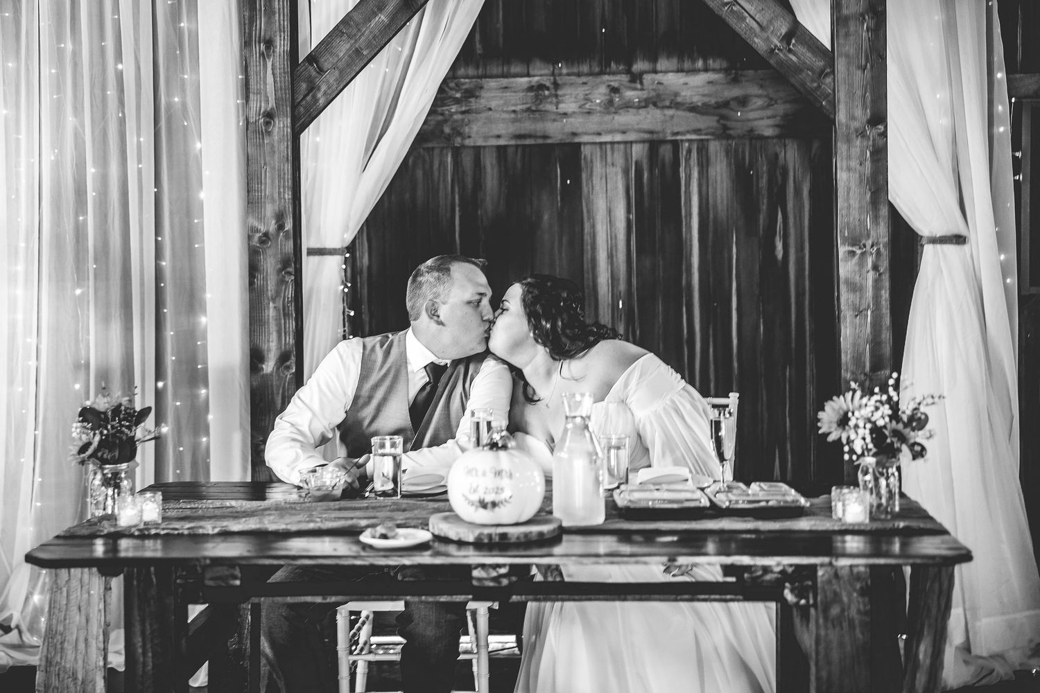 Black and white panorama of a rustic barn wedding reception with elegant decor.