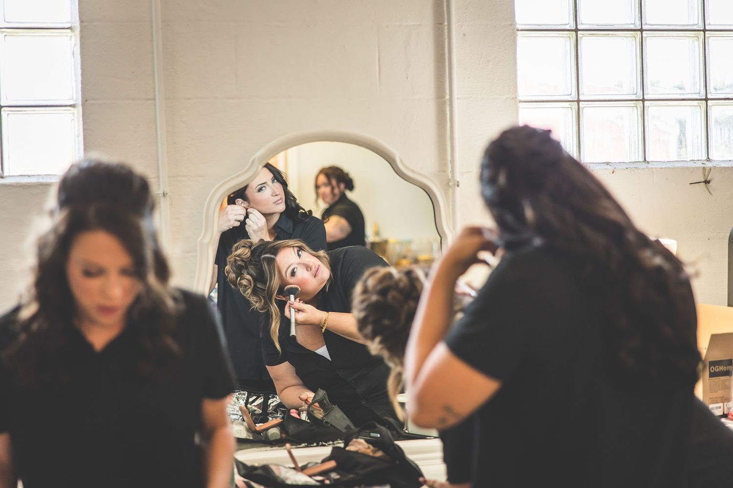 Wedding party getting ready in a bright indoor space with natural window light.