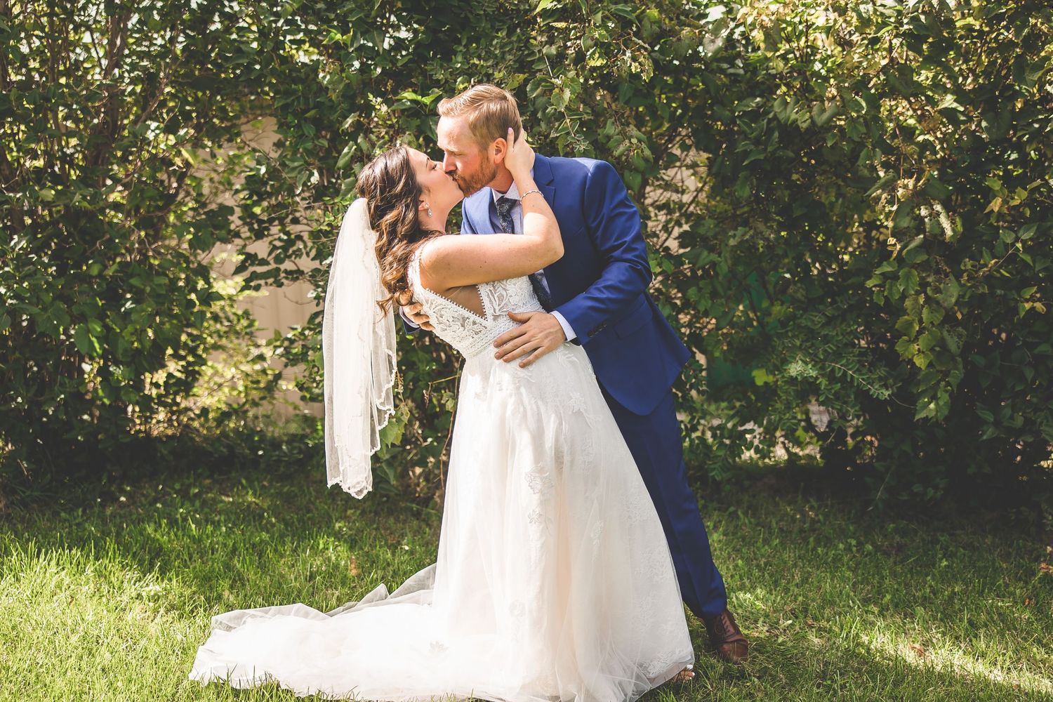 Couple sharing romantic moments in a garden setting with lush greenery and natural lighting.