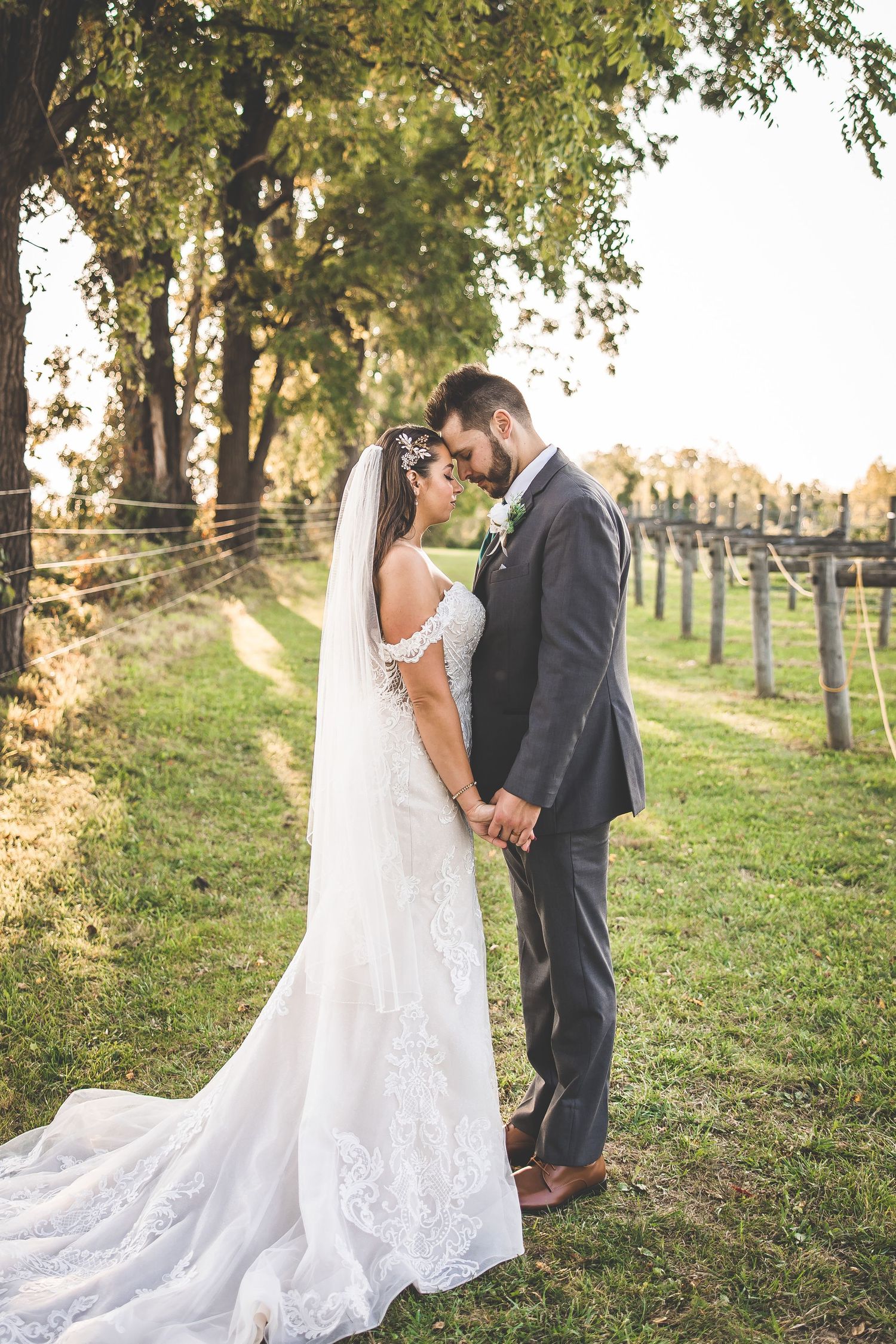 Newlyweds share intimate moments on a grassy hillside during their wedding photoshoot.