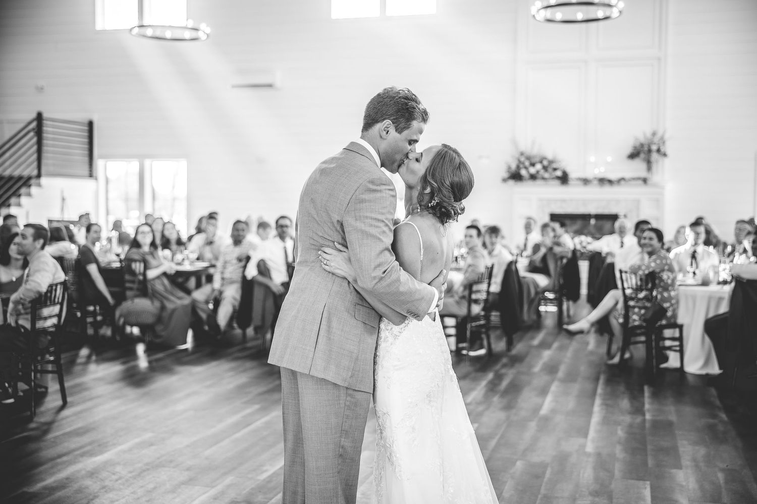 Wedding celebration on a polished dance floor with circular lighting fixtures overhead.