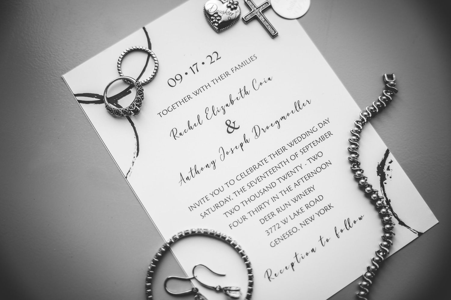 Black and white wedding invitation with elegant calligraphy and decorative rings.