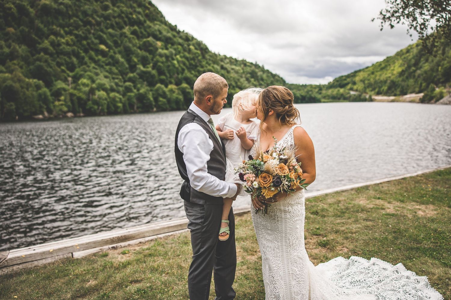Lakeside wedding photos with mountains and dramatic cloudy skies.