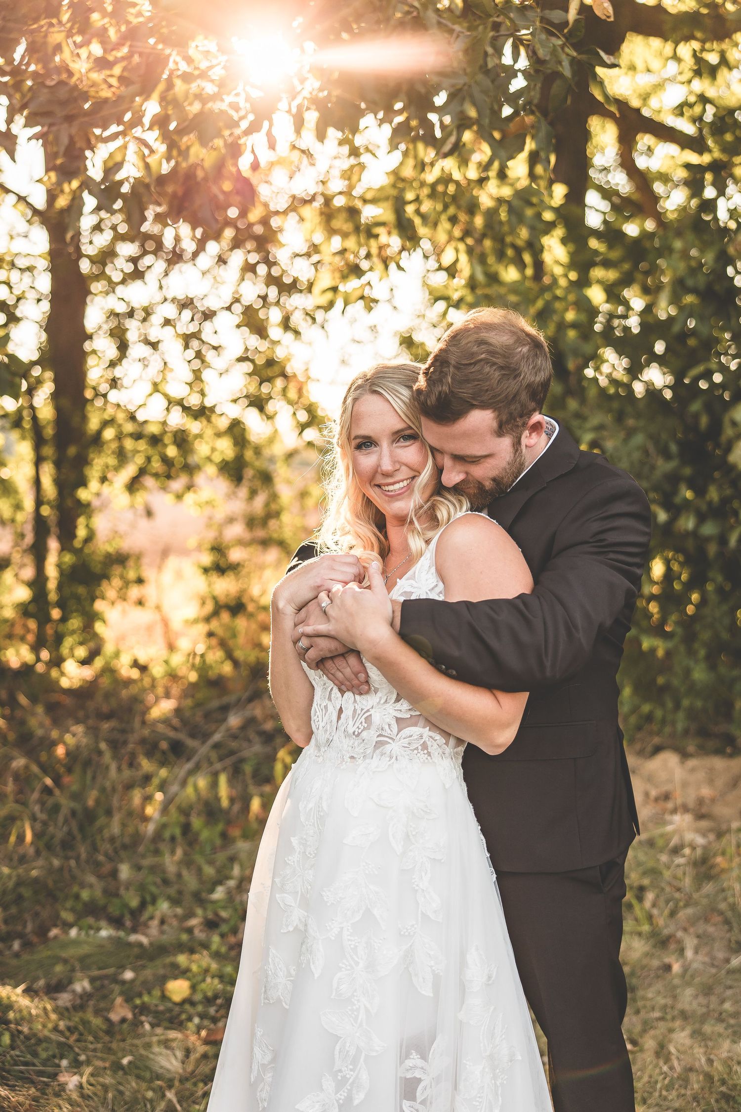 Romantic sunset portrait of couple embracing in golden backlit forest setting.