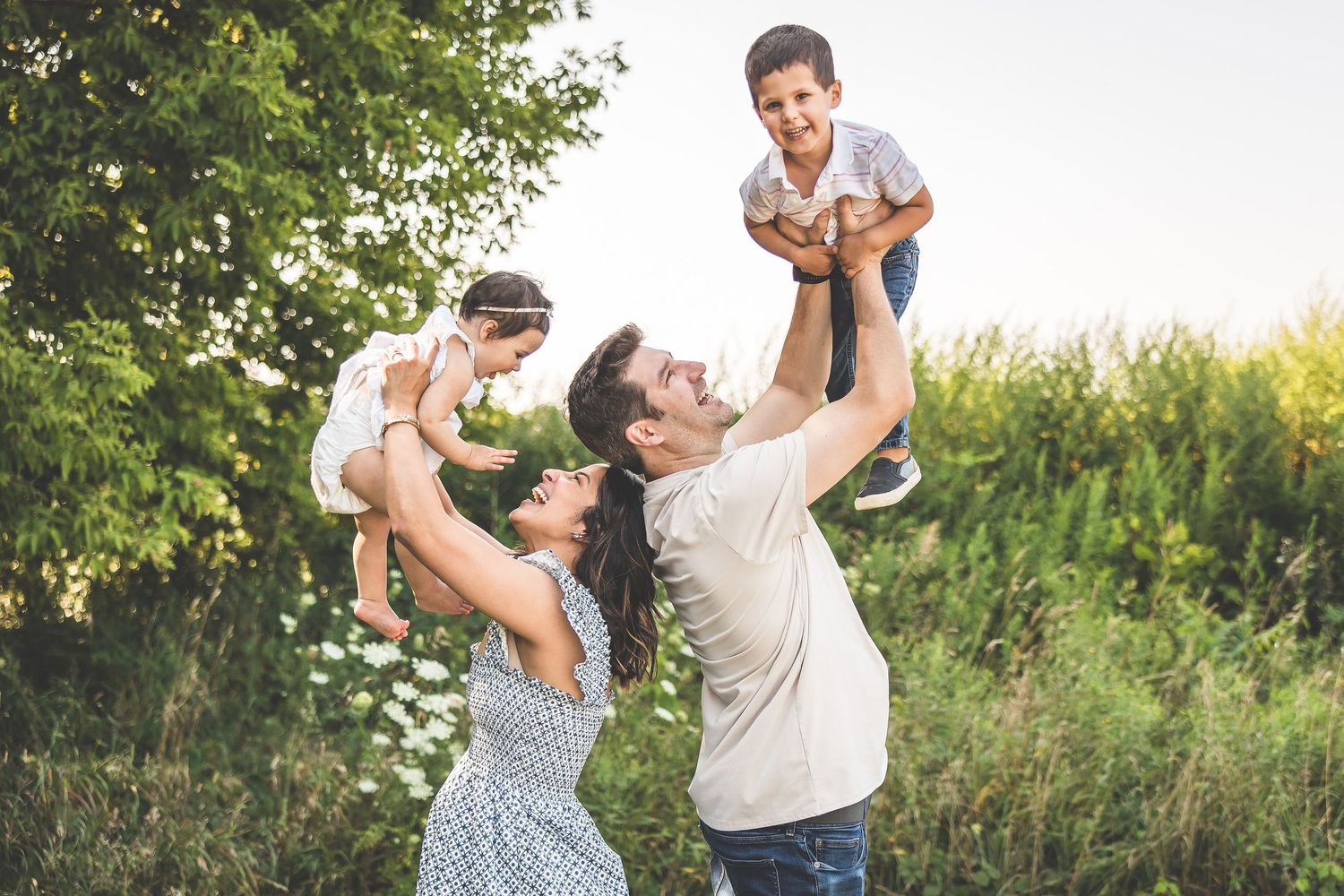 Family having fun and playing together in a lush green outdoor setting during golden hour.