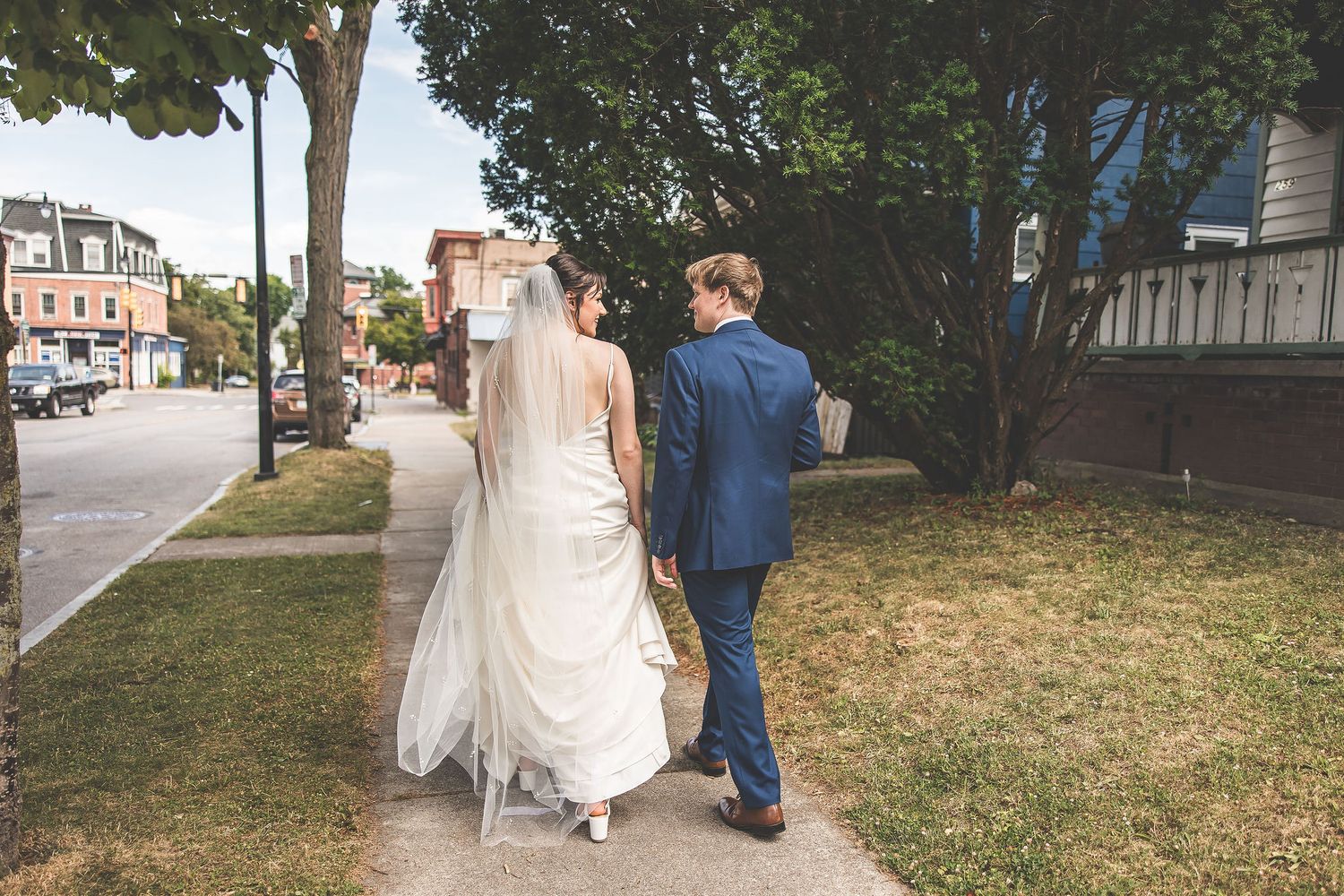 Couple walks along tree-lined pathway during wedding photo session.
